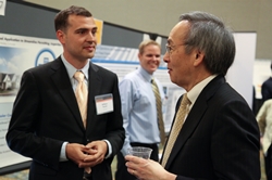 Photo of two men talking in front of a poster display.